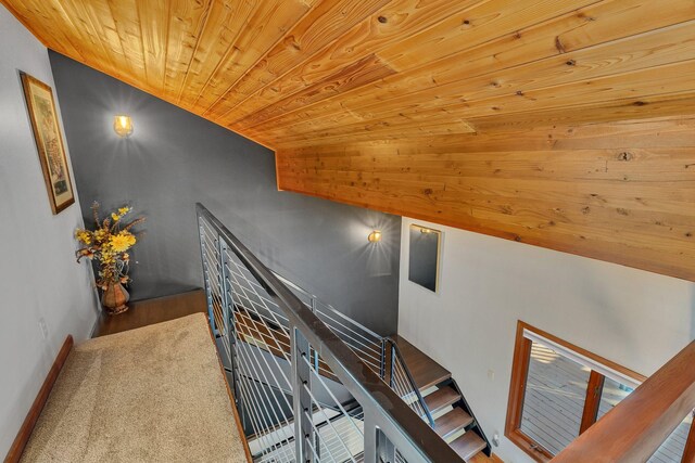 stairway with wood-type flooring, wood ceiling, and lofted ceiling