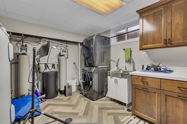 laundry room with cabinets, stacked washer and dryer, and sink