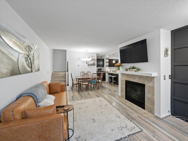 living room featuring a tile fireplace, a textured ceiling, and light wood-type flooring