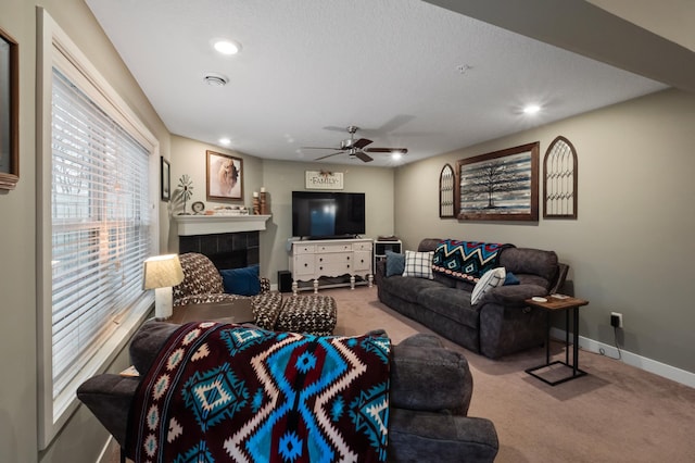 carpeted living room featuring a textured ceiling, a tile fireplace, and ceiling fan