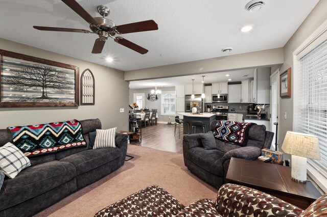 living room with hardwood / wood-style flooring, plenty of natural light, and ceiling fan with notable chandelier