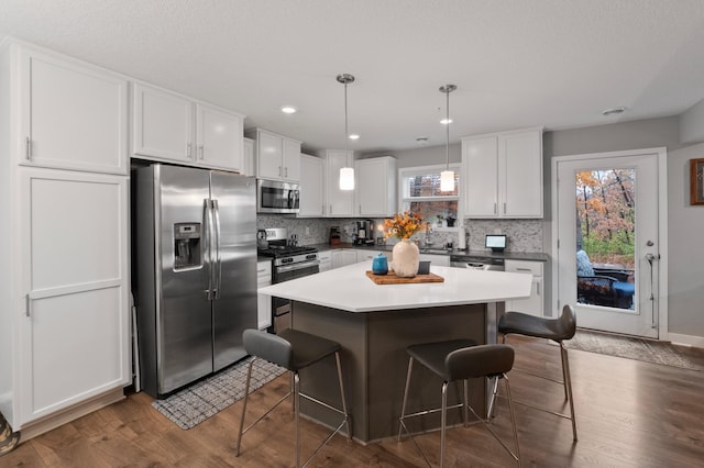 kitchen with a wealth of natural light, pendant lighting, white cabinets, and stainless steel appliances