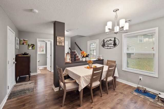 dining area with an inviting chandelier, a textured ceiling, and dark wood-type flooring