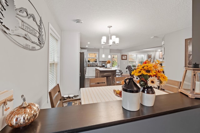 dining space with a textured ceiling and an inviting chandelier