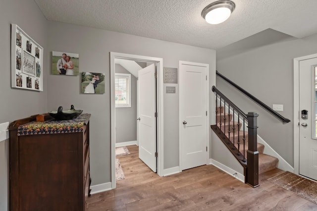 hallway with a textured ceiling and light wood-type flooring