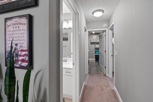 hallway featuring light carpet and a textured ceiling