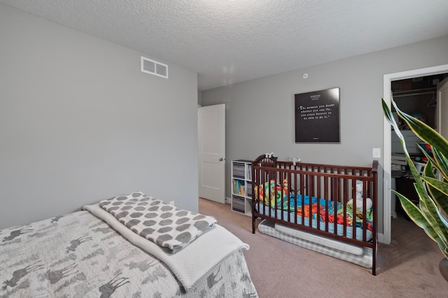 bedroom featuring a textured ceiling and light colored carpet