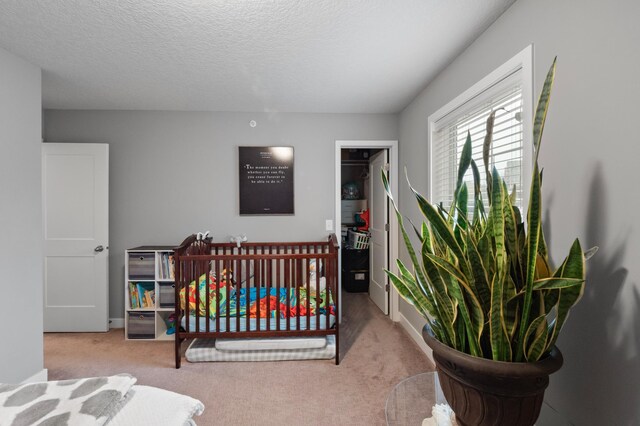 carpeted bedroom with a textured ceiling and a crib