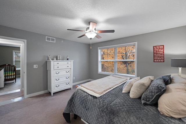 bedroom with a textured ceiling, carpet floors, and ceiling fan