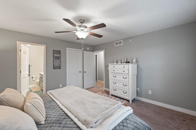 carpeted bedroom featuring ceiling fan, a textured ceiling, and ensuite bath