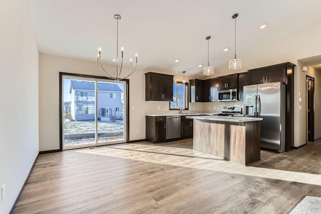 kitchen featuring a center island, stainless steel appliances, light hardwood / wood-style flooring, a chandelier, and decorative light fixtures