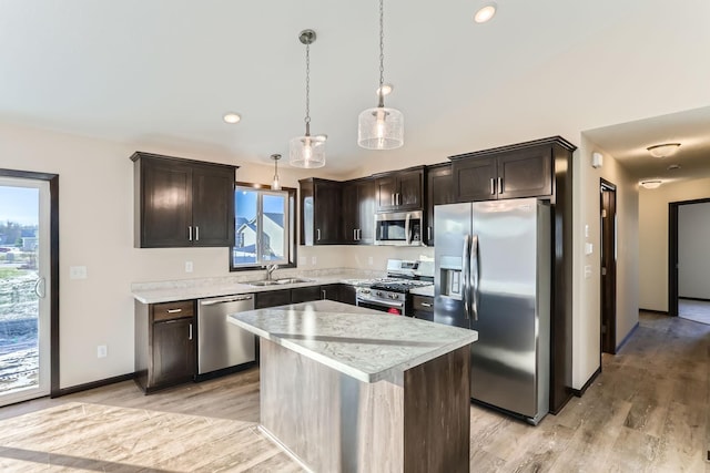 kitchen featuring dark brown cabinetry, hanging light fixtures, appliances with stainless steel finishes, a kitchen island, and light wood-type flooring