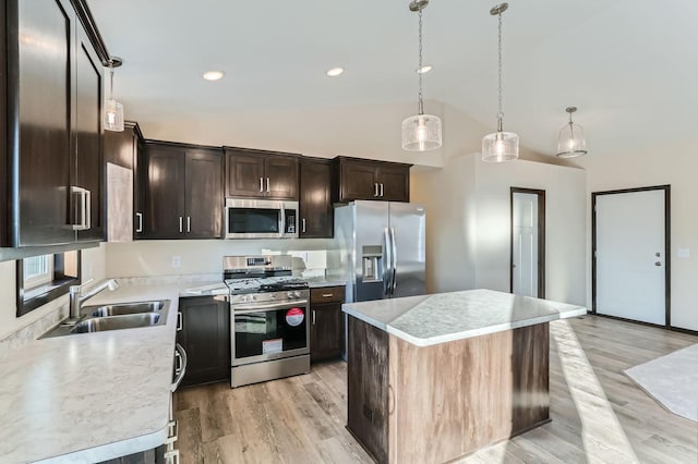 kitchen featuring sink, light hardwood / wood-style flooring, pendant lighting, a kitchen island, and appliances with stainless steel finishes