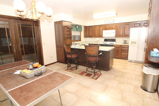 kitchen with an inviting chandelier, kitchen peninsula, hanging light fixtures, a breakfast bar, and white appliances