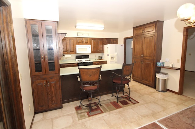 kitchen with white appliances, a breakfast bar area, and light tile patterned flooring