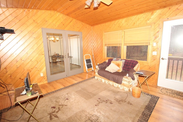 sitting room with lofted ceiling, wood ceiling, wood walls, hardwood / wood-style flooring, and ceiling fan