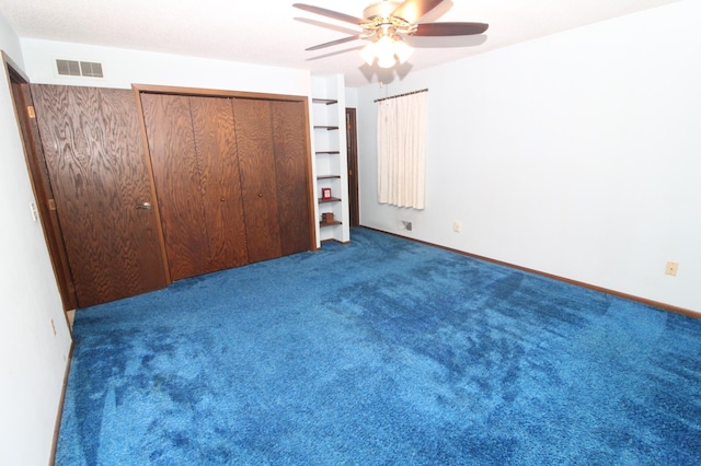 unfurnished bedroom featuring dark colored carpet, ceiling fan, and a closet