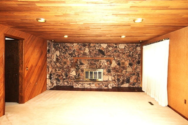 basement featuring a stone fireplace, carpet, wood walls, and wooden ceiling