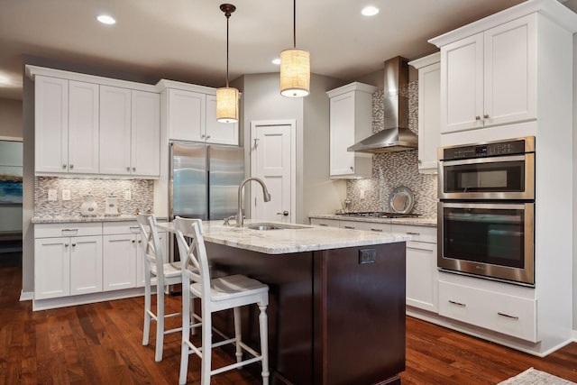 kitchen featuring hanging light fixtures, dark hardwood / wood-style flooring, appliances with stainless steel finishes, white cabinetry, and wall chimney exhaust hood