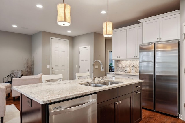 kitchen with appliances with stainless steel finishes, sink, pendant lighting, and white cabinets