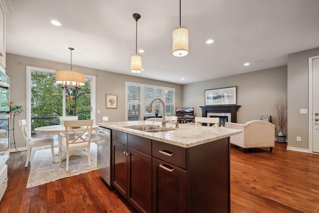 kitchen featuring light stone countertops, sink, dark hardwood / wood-style flooring, hanging light fixtures, and dark brown cabinetry