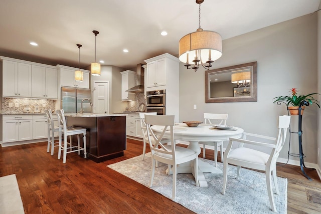 dining room featuring sink, an inviting chandelier, and dark hardwood / wood-style floors