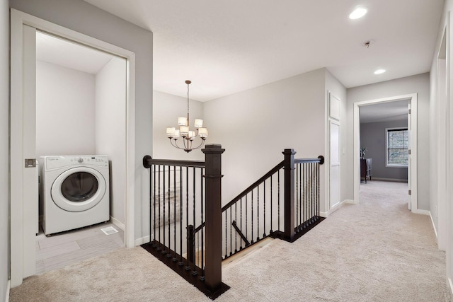 hallway with washer / dryer, a chandelier, and light colored carpet