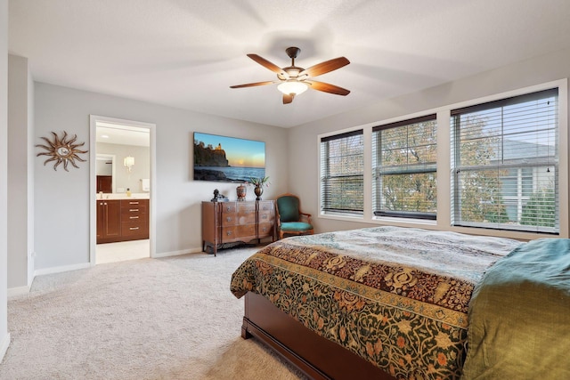 bedroom with ensuite bath, multiple windows, light colored carpet, and ceiling fan