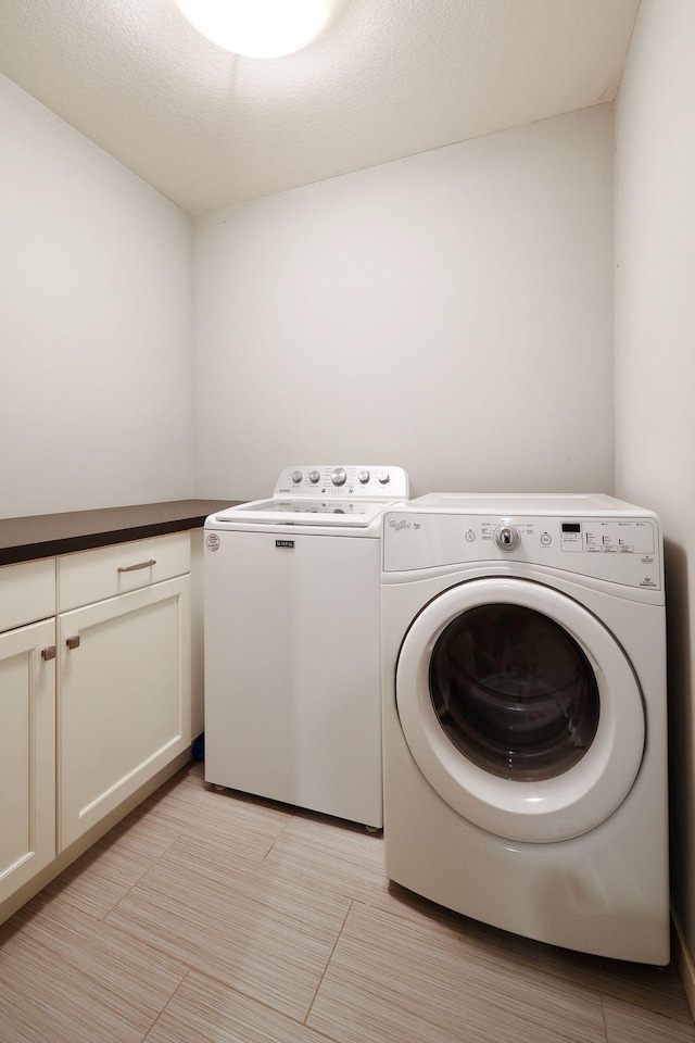 clothes washing area featuring cabinets, a textured ceiling, and washing machine and clothes dryer