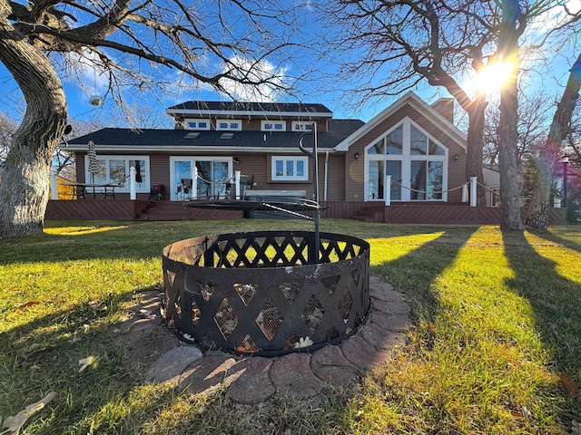 back of house with a chimney, a yard, and a deck