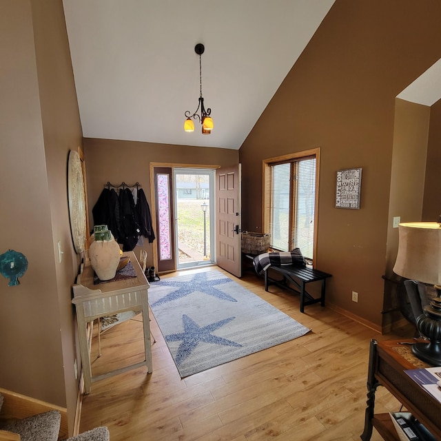 foyer entrance featuring high vaulted ceiling, light hardwood / wood-style floors, and an inviting chandelier