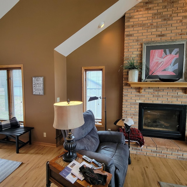 living room with hardwood / wood-style flooring, lofted ceiling, and a brick fireplace