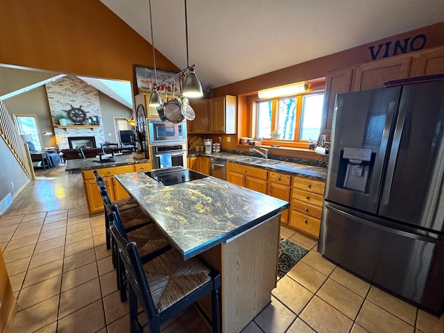 kitchen with a brick fireplace, a breakfast bar, stainless steel appliances, light tile patterned floors, and a kitchen island