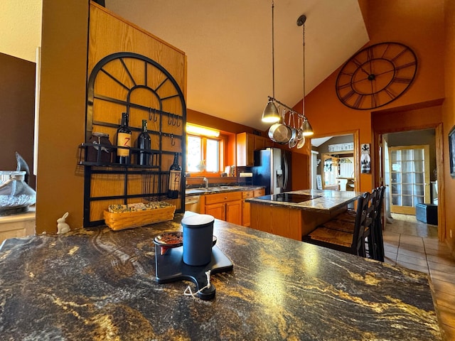 kitchen featuring stainless steel fridge, a kitchen breakfast bar, sink, high vaulted ceiling, and a center island