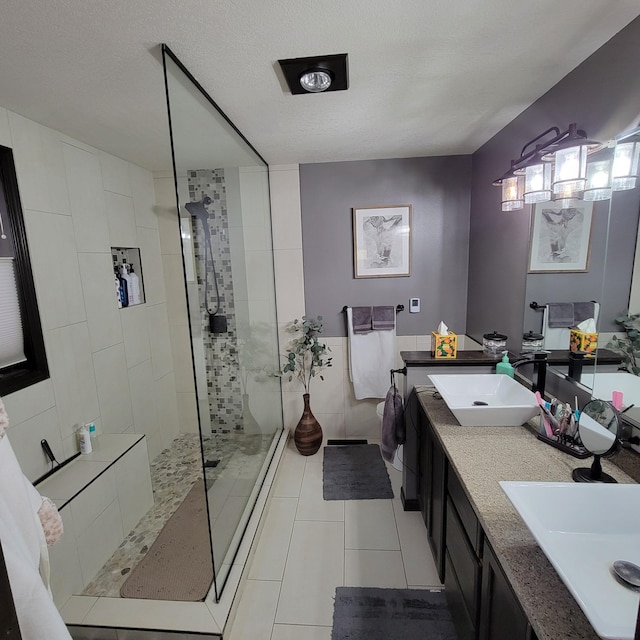 bathroom with tile patterned floors, a tile shower, vanity, and a textured ceiling