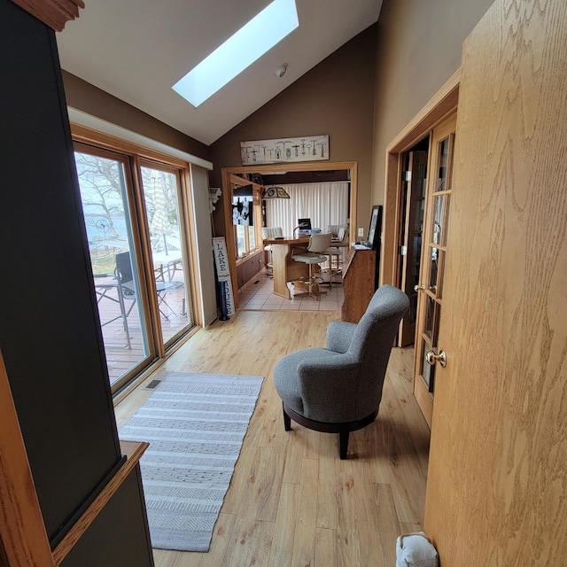 interior space featuring french doors, light wood-type flooring, and lofted ceiling with skylight