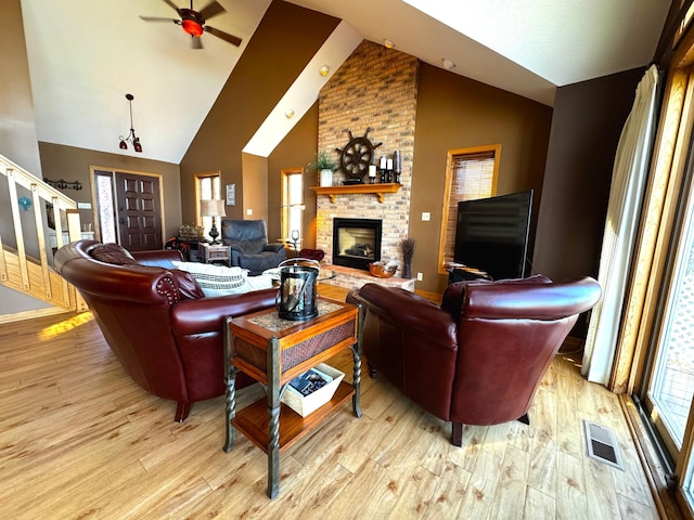 living room with ceiling fan, a fireplace, light hardwood / wood-style floors, and vaulted ceiling