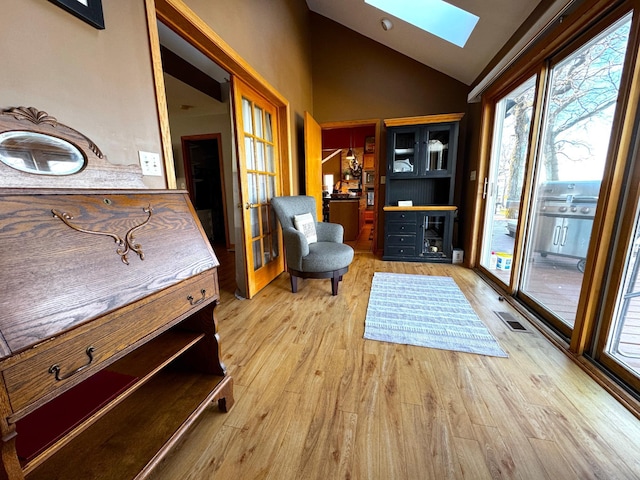 sitting room with vaulted ceiling with skylight and light hardwood / wood-style floors