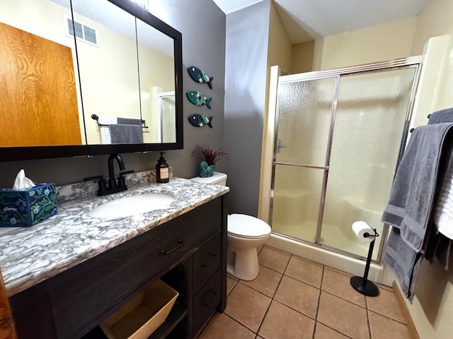 bathroom featuring tile patterned floors, vanity, a shower with shower door, and toilet