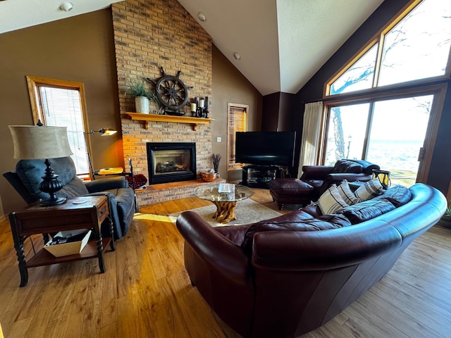 living room with high vaulted ceiling, a fireplace, and wood finished floors