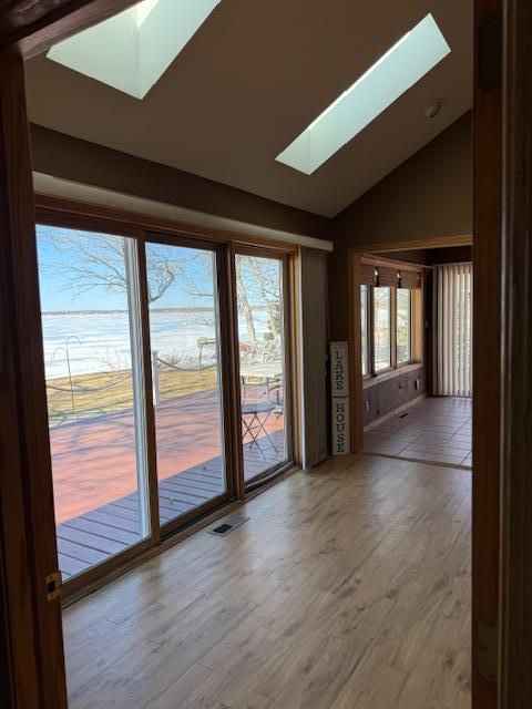 spare room featuring lofted ceiling with skylight, visible vents, and wood finished floors