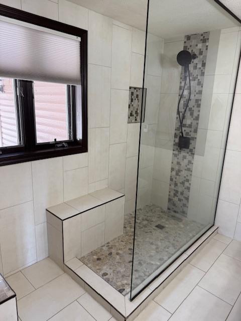 full bath featuring a healthy amount of sunlight, a tile shower, and tile patterned floors