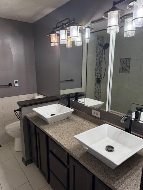 full bath with tile patterned flooring, a sink, toilet, and double vanity