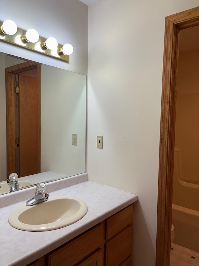 bathroom with toilet, a bath, and vanity