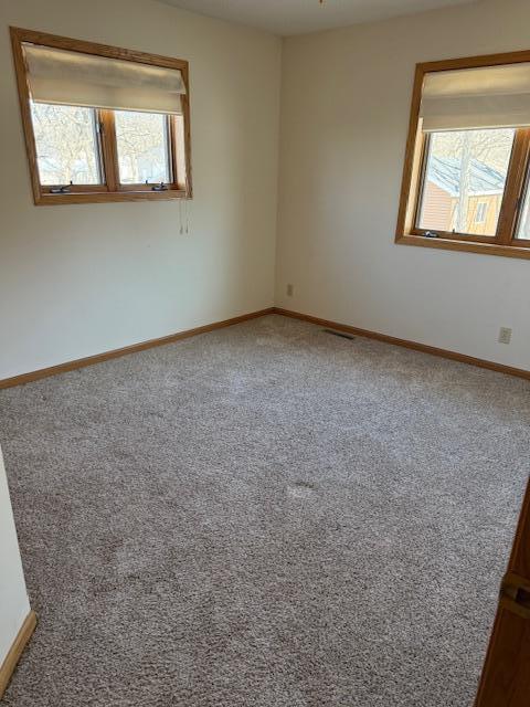 empty room featuring carpet floors and baseboards