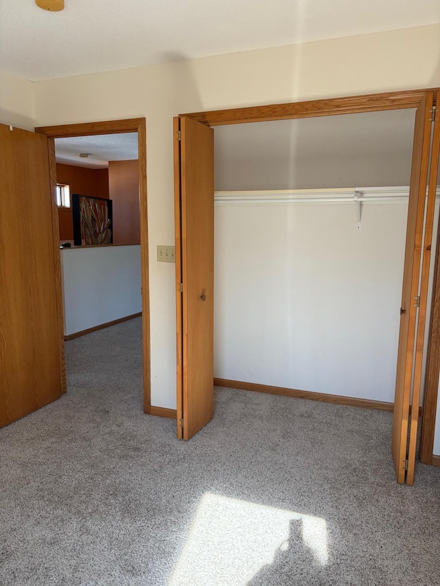 unfurnished bedroom with a closet, carpet, and baseboards