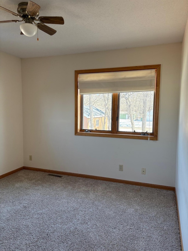 unfurnished room featuring carpet, visible vents, and baseboards