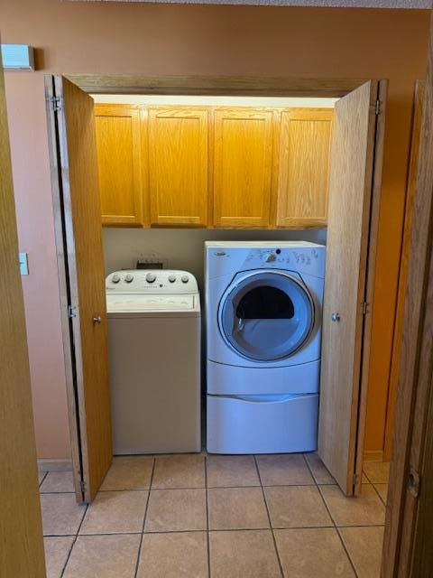 laundry room with light tile patterned floors, separate washer and dryer, and cabinet space