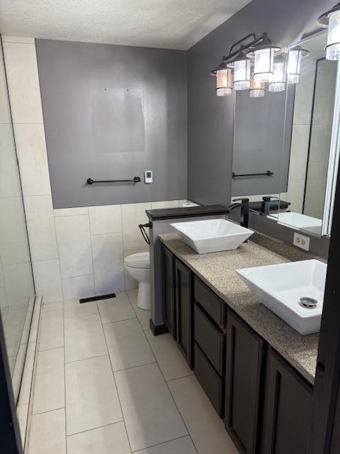 145 Bay View Rd, Ottertail, MN 56571 - full bathroom featuring toilet, double vanity, tile patterned flooring, tile walls, and a textured ceiling