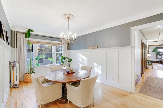 dining space with crown molding, light wood-type flooring, and a notable chandelier